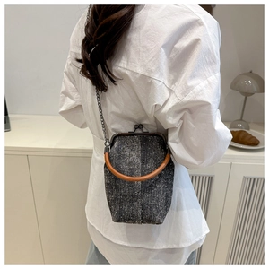 Détail du sac seau en tweed avec fermoir bronze et bandoulière chaîne sur un modèle