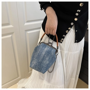 Detail of vintage denim bucket bag featuring a wash texture and metallic clasp closure