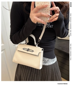 Detail of cream white Kelly bag showing silver lock clasp and adjustable shoulder strap