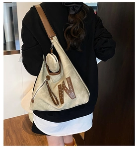 Detail of large canvas tote bag with brown leather straps and W letter rivet decoration