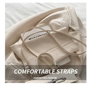 Detail of creamy white litchi leather bag with silver buckle on beige blazer