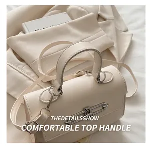 Close-up of cream leather handbag with gold metal clasp on a textured blazer background