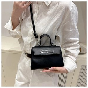 Detail of elegant black leather handbag with metallic clasp and adjustable strap