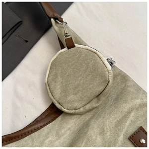 Detail of khaki canvas tote bag featuring a round detachable mini coin purse and silver zipper