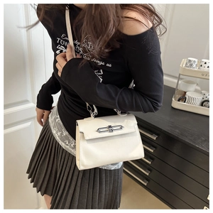 Close-up of cream square handbag with silver chain lock shown on model for size and style