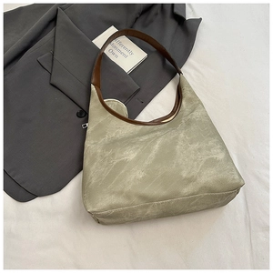 Detail of hobo underarm bag in grey-green matte finish with brown leather shoulder strap