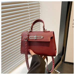 Detail of burgundy trapezoid handbag with silver bar lock and smooth leather finish