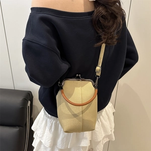 Vertical beige canvas crossbody bag with leather handle and metal clasp closure