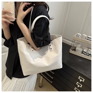 Detail of white woven leather tote bag with silver metal buckles and shoulder straps