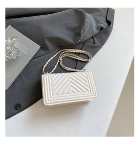 Detailed close-up of ivory V-quilted faux leather crossbody bag with gold chain strap