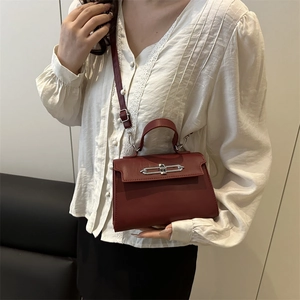 Sac bandoulière bordeaux minimaliste avec détails argentés porté par un mannequin