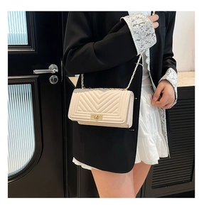Gros plan sur un sac bandoulière crème avec surpiqûres en V et fermoir doré chic