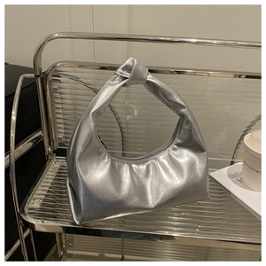 Close-up of metallic silver knot handbag on a clear display stand in modern style