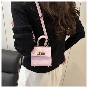 Pink mini crossbody bag with crocodile texture and gold lock hardware on a model