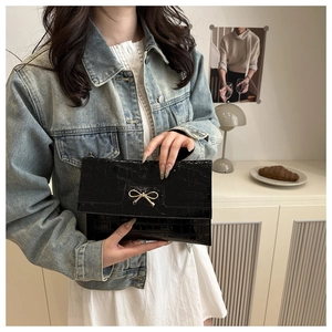 Detailed macro view of black crocodile pattern leather bag with a golden bow metal buckle