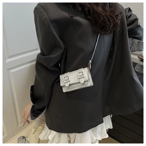 Silver mini crossbody bag with carbon fiber texture on a model in a grey blazer