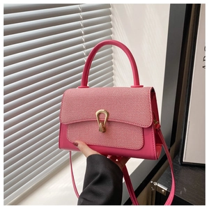 Close-up of pink crossbody bag with woven fabric texture and gold rotating buckle