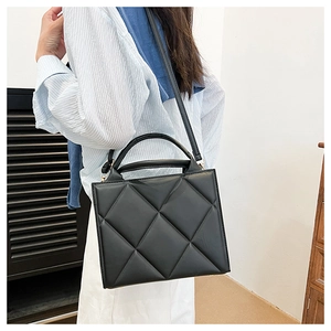 Detail of black quilted leather handbag showing the elegant diamond pattern and shoulder strap