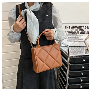 Minimalist caramel brown quilted crossbody bag shown in a stylish lifestyle setting