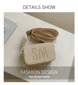 Close-up of beige crossbody bag with SM rivet logo and wide fabric shoulder strap