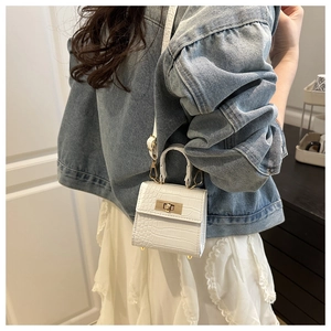 Detail of white crocodile embossed mini handbag with gold twist lock and metal bottom studs