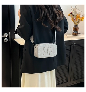 Silver glitter camera bag with SM rivet lettering worn by a model in a stylish interior