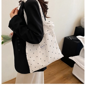 Détail du sac cabas blanc à fleurs montrant sa taille et sa texture portées à l'épaule