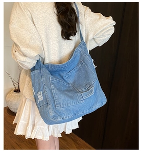 Detailed view of vintage washed blue denim crossbody bag with multiple pockets on model