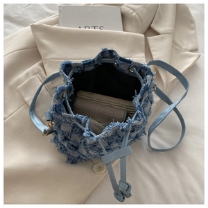 Dettaglio della borsa a secchiello in denim a scacchi con interno spazioso per cellulare