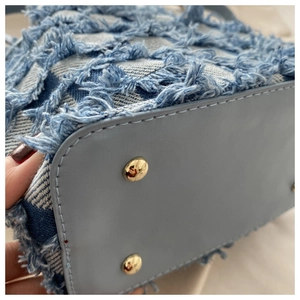 Dettaglio della base della borsa in pelle azzurra con quattro piedini in metallo oro