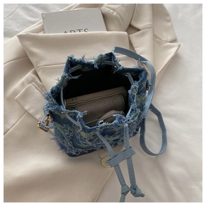 Vista macro di una borsa a secchiello in denim con bordi sfrangiati e dettagli a stella