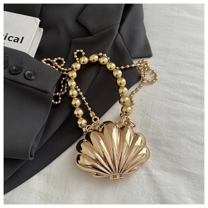 Detailed view of a gold shell-shaped clutch with bead handle and metallic finish