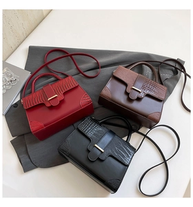 Detailed view of three small bags in red, brown, and black with crocodile texture and gold locks