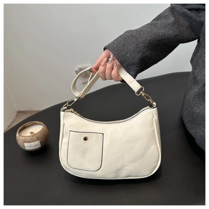 Close-up of beige lychee grain PU leather bag with gold buckle and adjustable strap