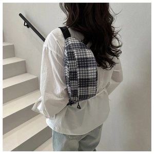 Détail du sac de poitrine à carreaux avec motif noir et blanc et bandoulière réglable