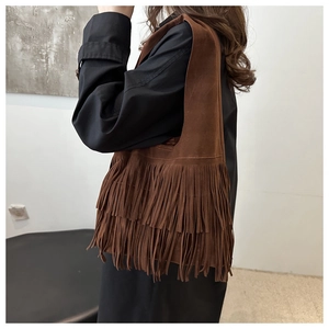 Detail of bohemian dark brown suede bag featuring tiered tassels and matte texture finish
