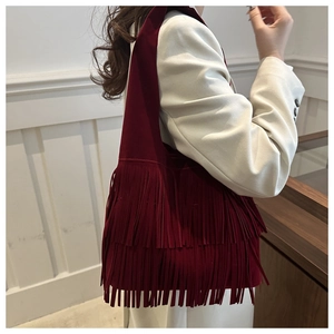 Detail of burgundy faux suede shoulder bag with long fringes and bohemian vintage texture