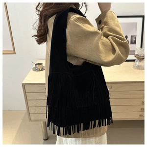 Detail view of the black suede bag featuring layered long tassels and a spacious design