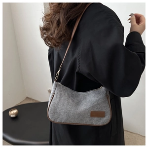 Detail of grey woven hobo bag showing brown leather strap and zip closure on model
