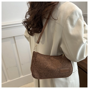Detail of brown woven shoulder bag with leather trim and gold-tone metal zipper hardware