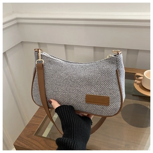 Close-up of gray twill texture bag with brown leather trim and golden zipper
