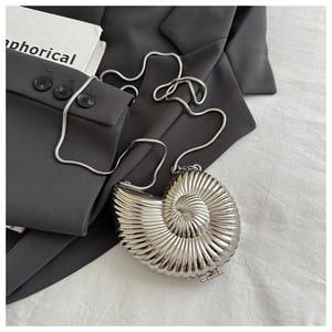 Macro shot of silver conch-shaped evening clutch with spiral texture and chain strap