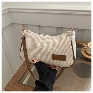 Detail of beige woven fabric bag with brown leather trim and fashion brand tag