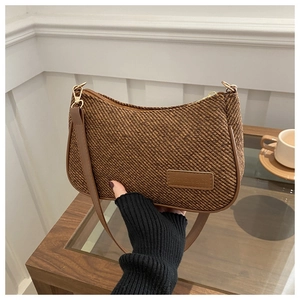 Close-up of brown woven shoulder bag with leather trim and gold fashion logo plate