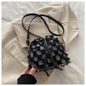 Detail of checkered bucket bag featuring raw-edged tweed texture and black leather drawstrings