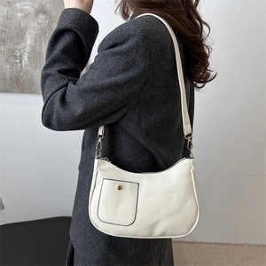 Sac sous le bras minimaliste en cuir crème avec boucles dorées sur un manteau gris