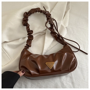 Macro detail of dark brown pleated leather shoulder bag with metallic triangular logo