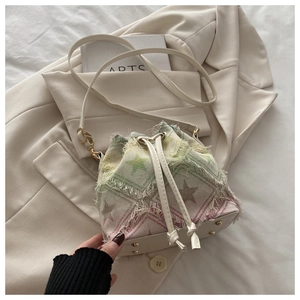 Detailed view of bucket bag featuring star pattern canvas, frayed edges, and metal feet
