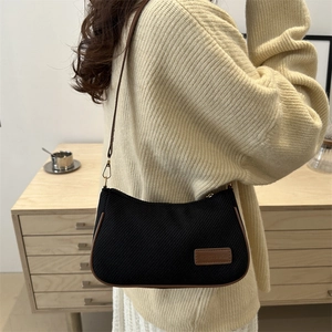 Minimalist black canvas underarm bag with brown leather trim and metal buckles