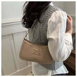 Detail of beige shoulder bag with golden bow buckle and smooth PU leather texture